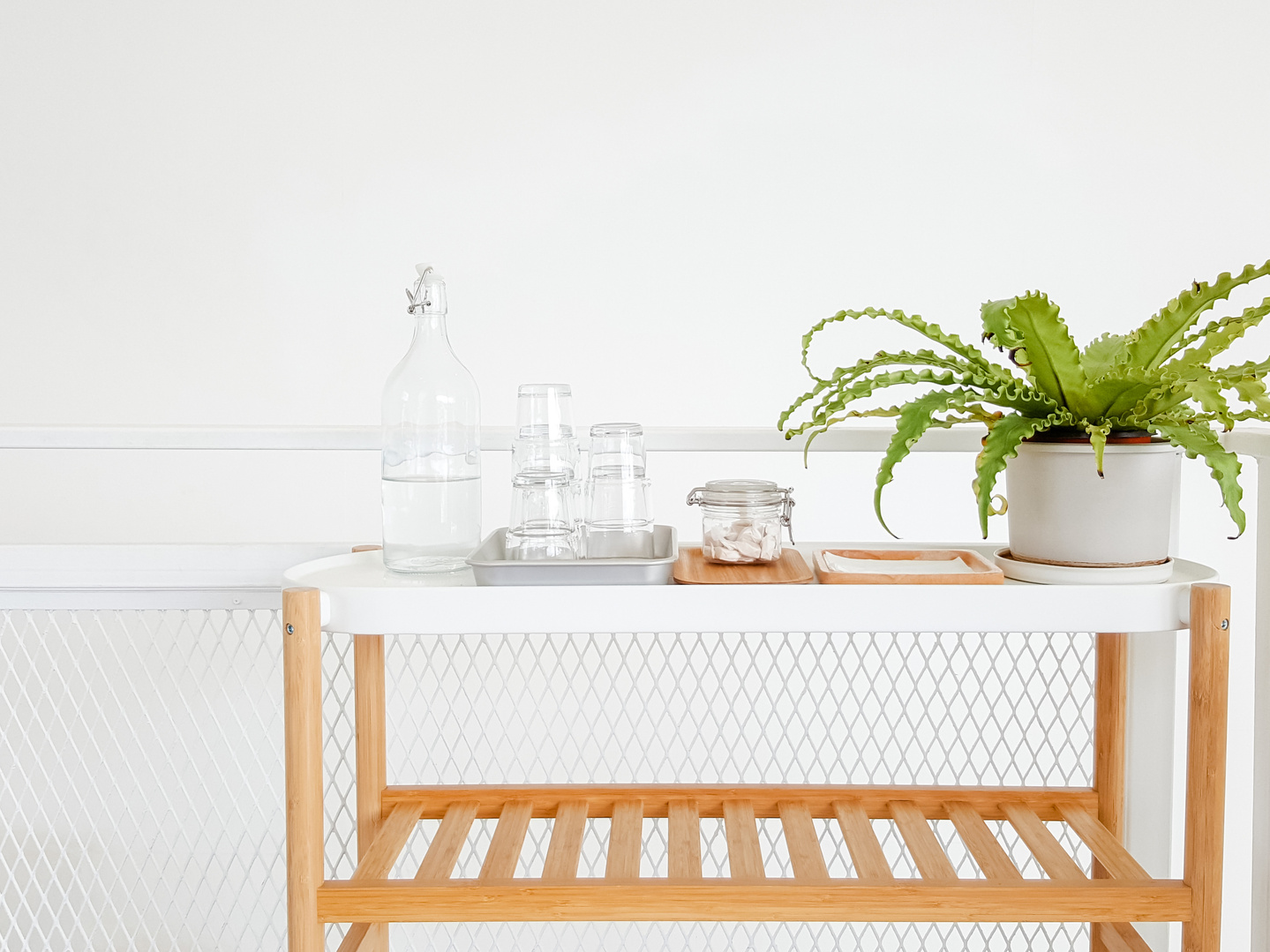 Bottle of Water on Wooden Table in Hotel White Room. Green Flowe